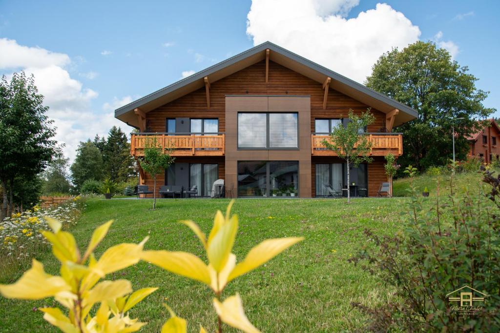 ein Haus auf einem Hügel mit einem grünen Garten in der Unterkunft Notre Chalet - Boutique Appartements 4 étoiles & Sauna in Les Fourgs