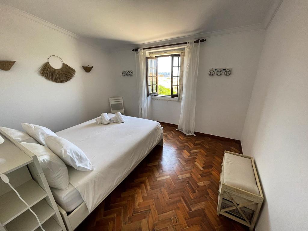 una camera da letto con un grande letto bianco e una finestra di Casa dos Rebolinhos a Sagres