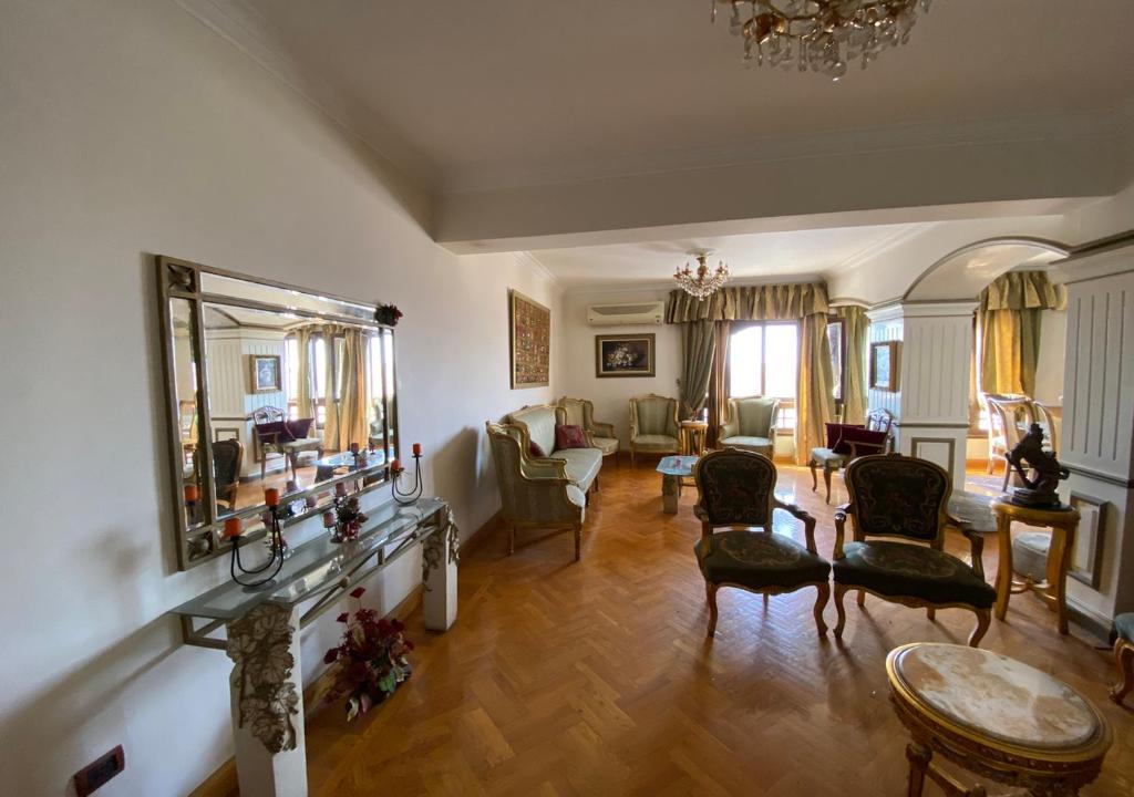 - un salon avec des chaises, une table et un miroir dans l'établissement Heliopolis pearl/ furnished apartment, au Caire