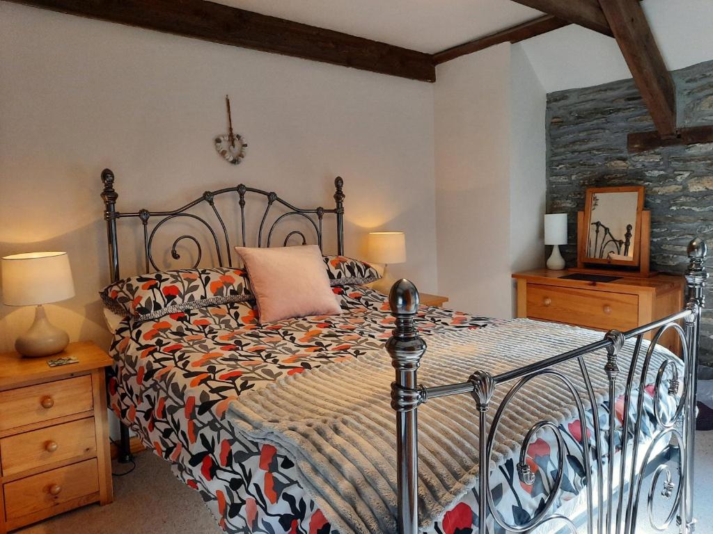 a bedroom with a bed with a comforter at Troedyrhiw Holiday Cottages in Cardigan