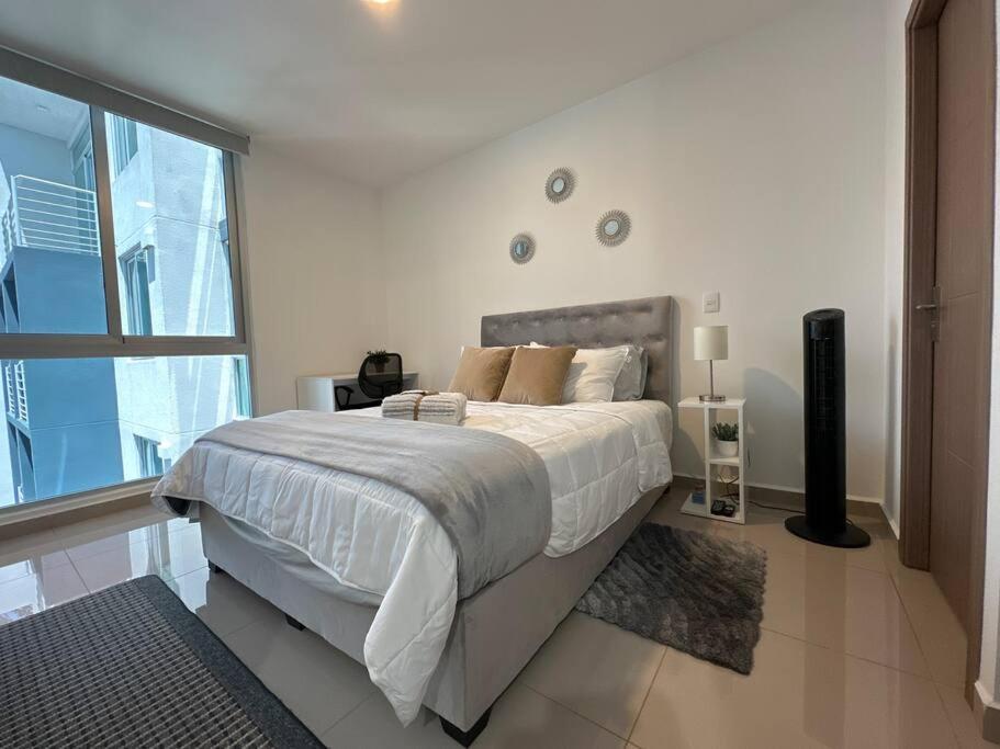 een slaapkamer met een groot bed en een groot raam bij New Luxury Apartment 12th Floor in San José