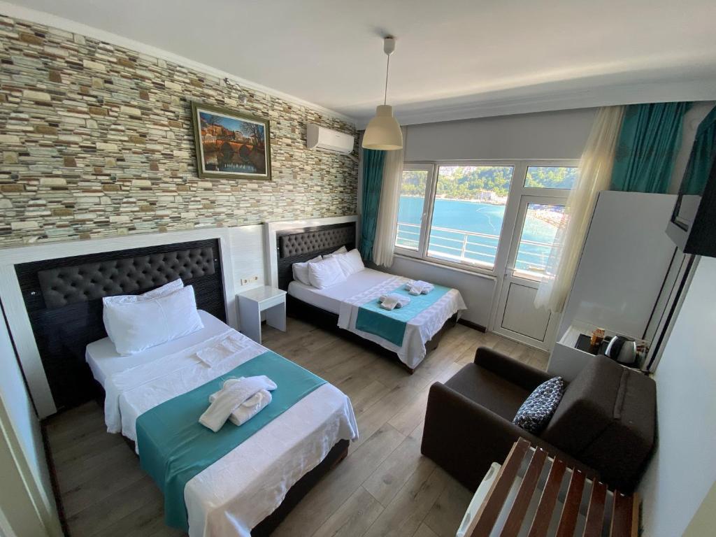 a hotel room with two beds and a chair at Marina Hotel in Amasra