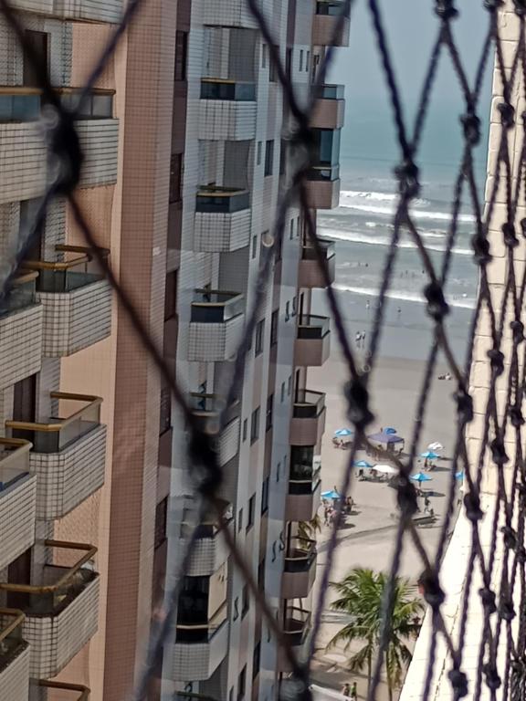- Vistas al edificio y a la playa a través de una valla en Frente ao mar na Praia Grande, en Praia Grande