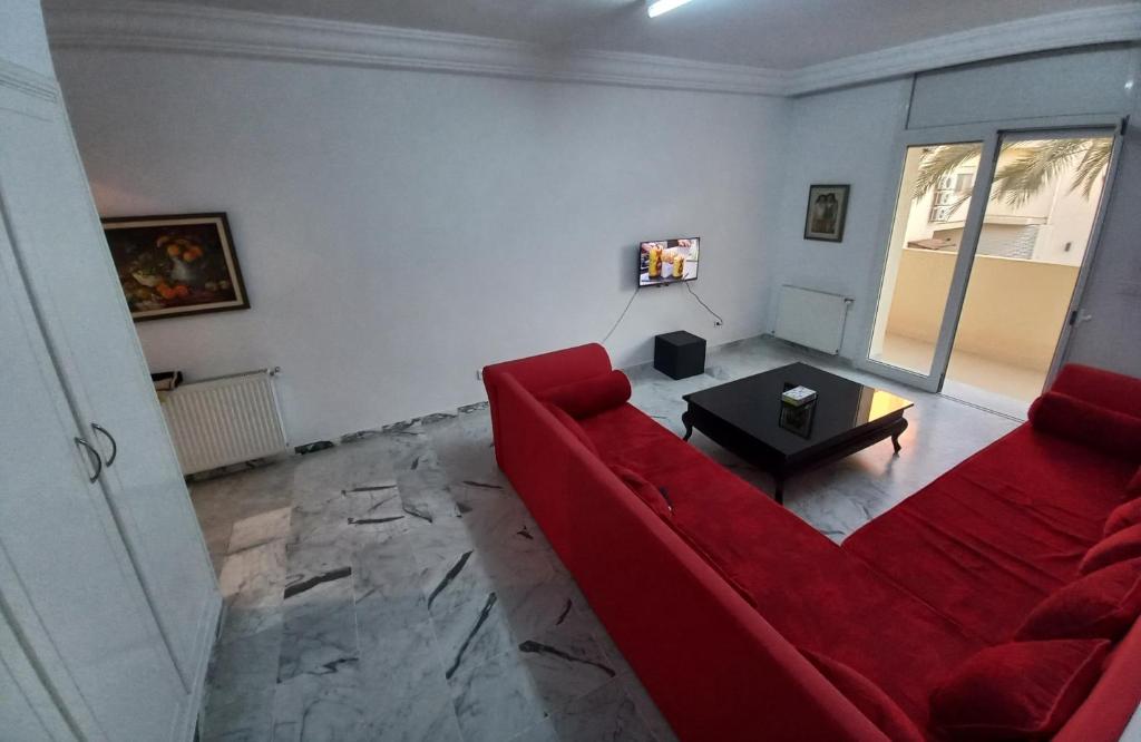 a living room with a red couch and a table at Nice inn appartment Lac 2 in El Aouina