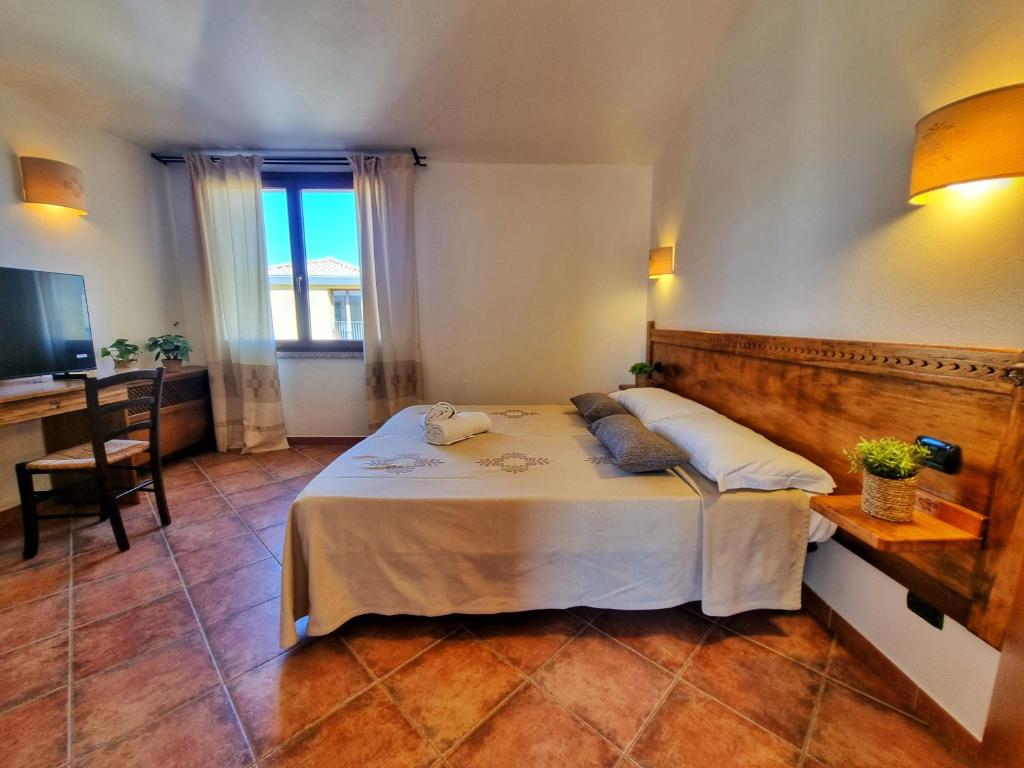 a bedroom with a bed and a desk and a television at Domos de Ammentos in Tortolì