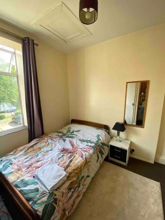 a bedroom with a bed and a mirror and a window at RHB Apartments in Leicester