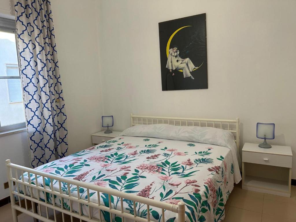 Il mare che ti Puglia في جينوسا مارينا: غرفة نوم مع سرير مع لحاف من الزهور