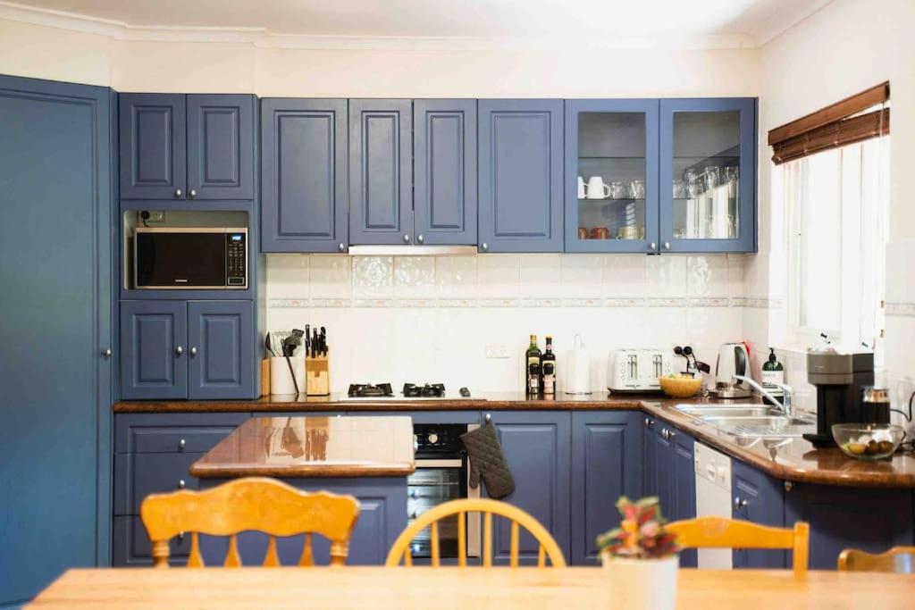 a kitchen with blue cabinets and a wooden table at 11 Guest, Xbox, Netflix, Close to Shops & Parks in Kingston 