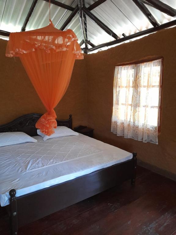 um quarto com uma cama com uma cortina laranja em Morakanda Eco Villa em Elpitiya