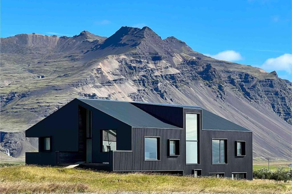 una casa negra frente a una montaña en The Blackhouse, en Höfn