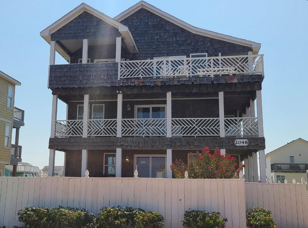 a large house with a balcony on top of a fence at Pierhouse Bed & Breakfast in Kill Devil Hills