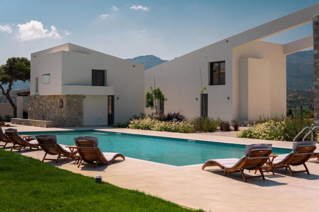 a villa with a swimming pool with chairs and a house at Itida Suites in Sitia