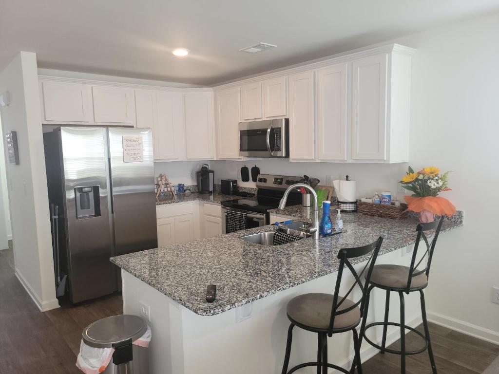 a kitchen with white cabinets and a counter with bar stools at SC 3745 New Townhouse Ft Jackson & USC in Columbia