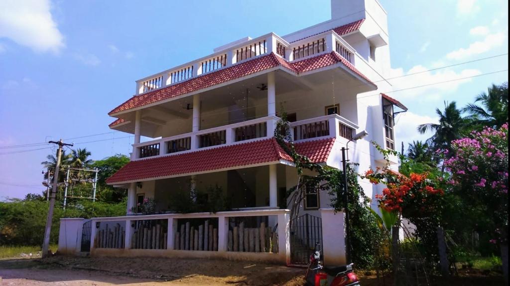 a white house with a balcony and a bike in front of it at Tranquility Guest House in Srīrangam