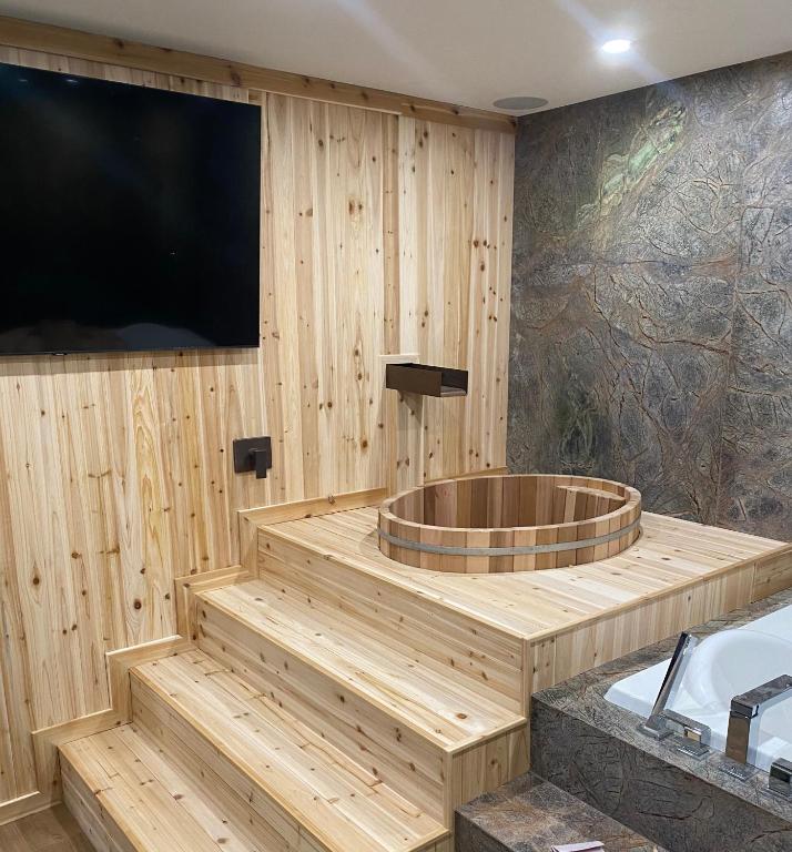 a bathroom with a tub and a large tv at Romantic Luxury Retreat with Private Sauna & Spa, Pet Friendly, Elkside Hideout B&B in Canmore