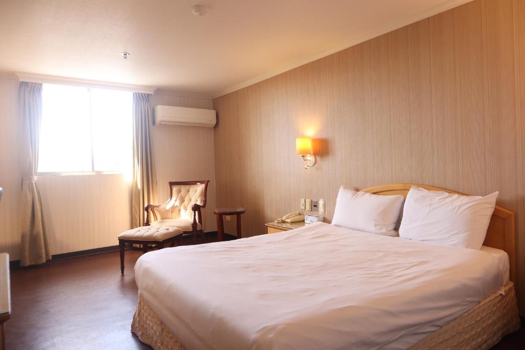 新竹市にあるエルメス ホテルの大きなベッドと椅子が備わるホテルルームです。
