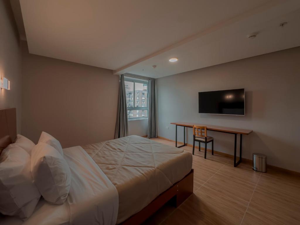 a bedroom with a bed and a desk and a television at MIRAFLORES CITY HOTEL in Lima
