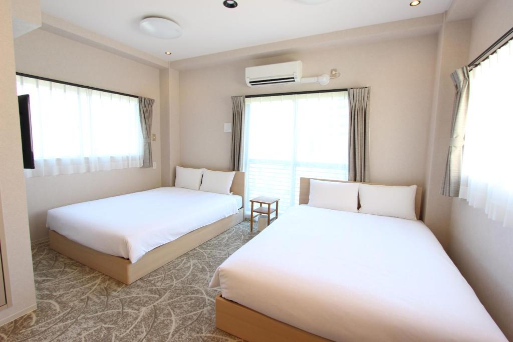 duas camas num quarto com duas janelas em Justin Fukuoka em Fukuoka