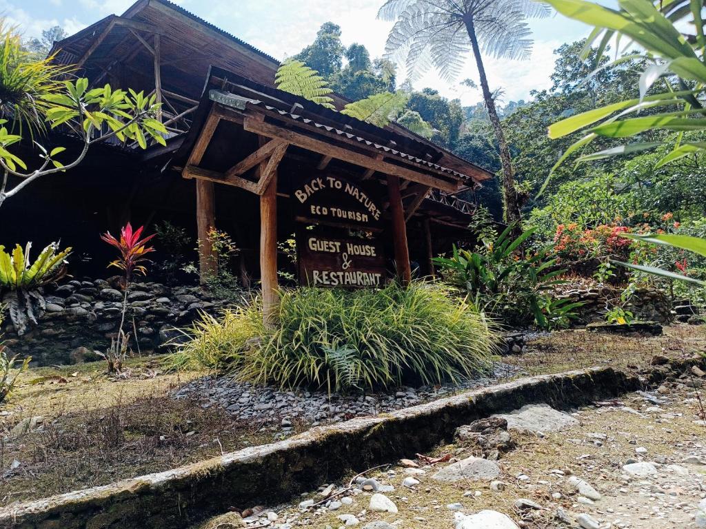 a sign in front of a building with plants at back to nature ecotourism in Bukit Lawang