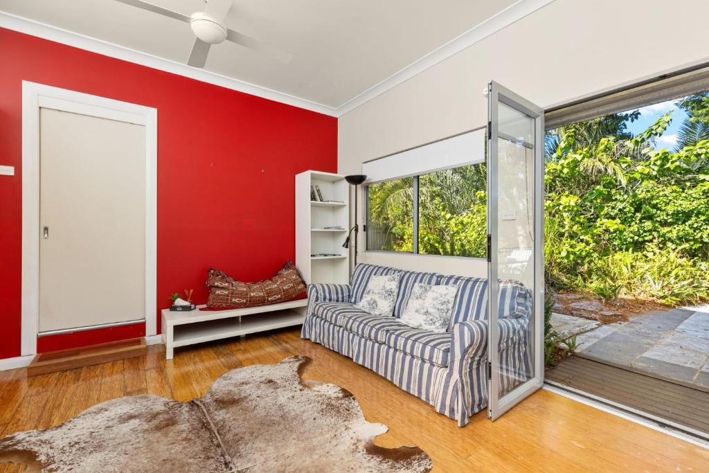 a red living room with a couch and a sliding glass door at Kingston Gardens by Experience Jervis Bay in Huskisson