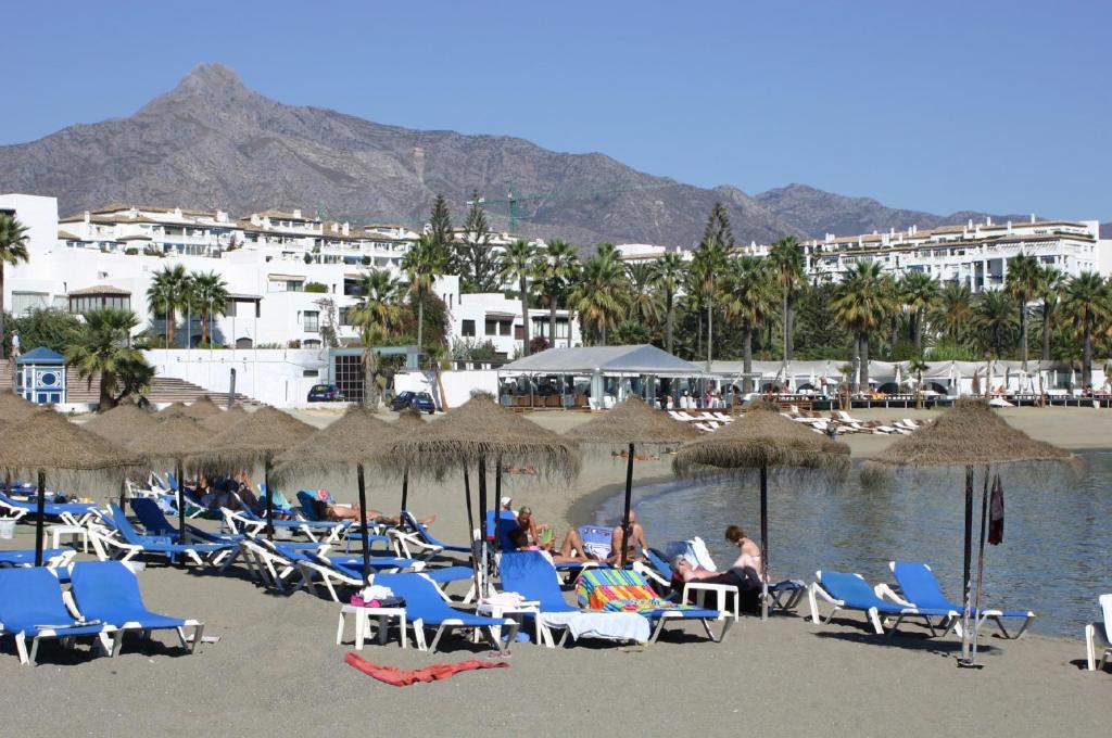 un grupo de sillas y sombrillas en una playa en Beachfront Puerto Banus en Marbella