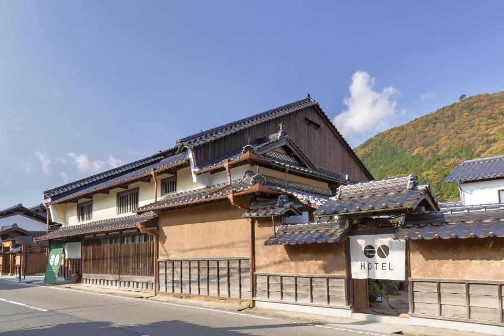 an old building with a mountain in the background at EN Takeda Castle Town Hotel in Asago