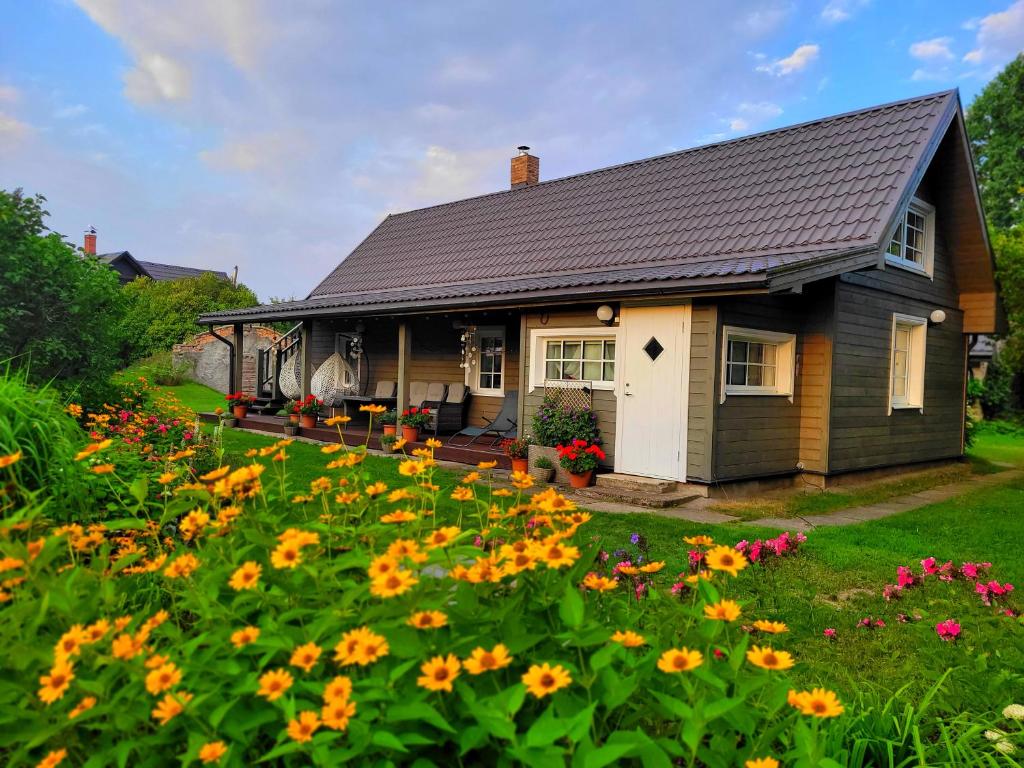 una pequeña casa con un campo de flores en NAMIŅŠ PIE JŪRAS, en Lapmežciems