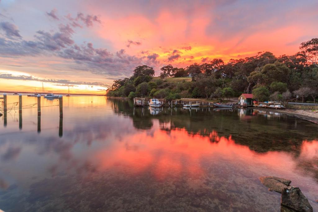 a sunset over a river with boats in the water at Jetty Road Retreat in Nungurner