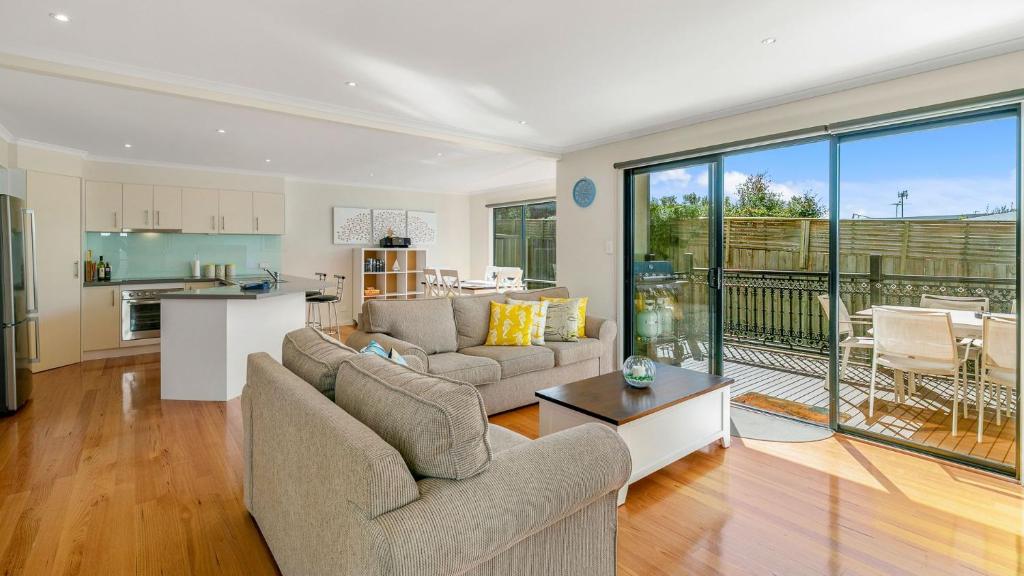 a living room with two couches and a kitchen at Island Holidayze in Cowes