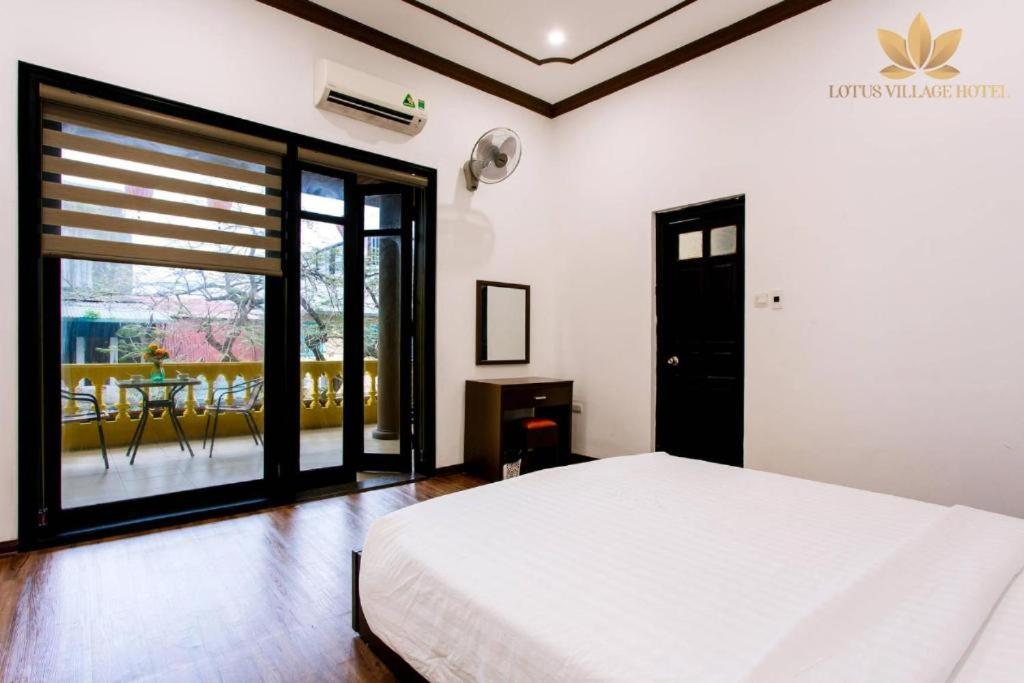 a bedroom with a white bed and a balcony at Lotus Village Hotel - 68 Hàng Bồ - by Bay Luxury in Hanoi
