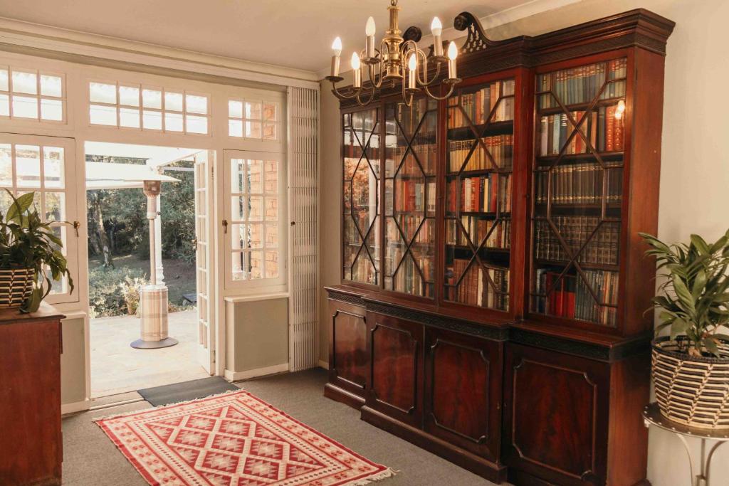 a library with a large wooden book case at Milestone Farm House in Balgowan