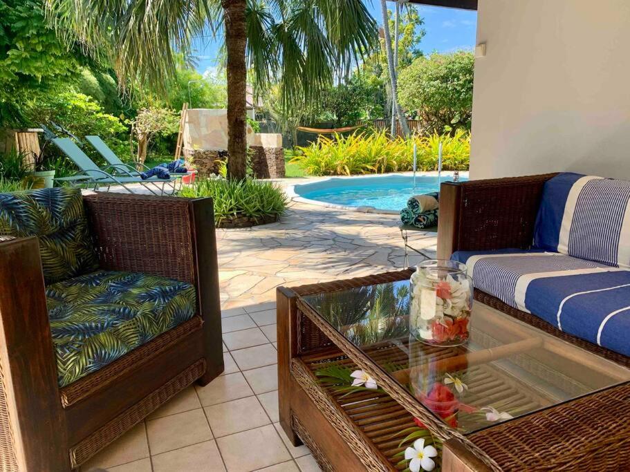 um pátio com 2 cadeiras, uma mesa e uma piscina em Villa Hoama Lodge Moorea em Teavaro