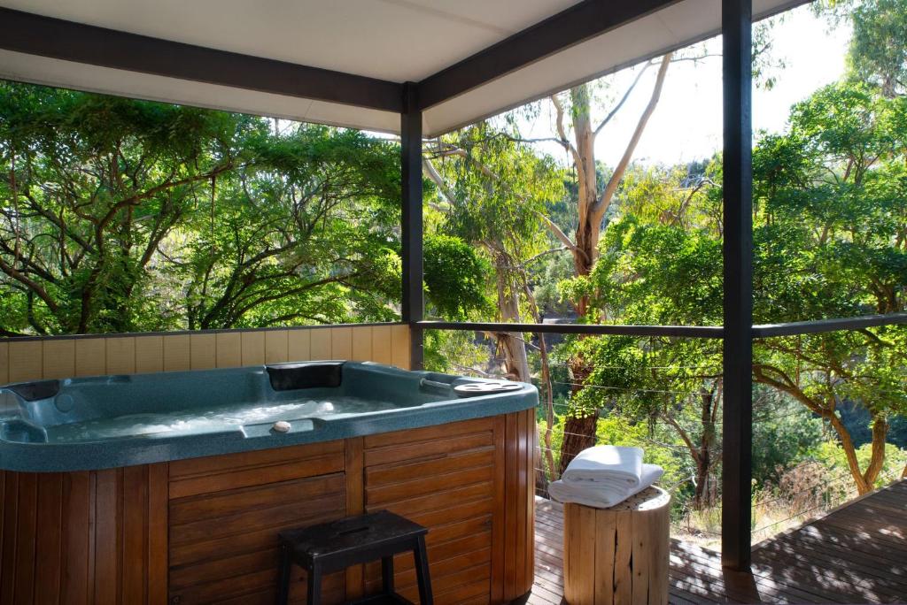a jacuzzi tub with a view of the trees at Swiss Mt Villa 2 in Hepburn Springs