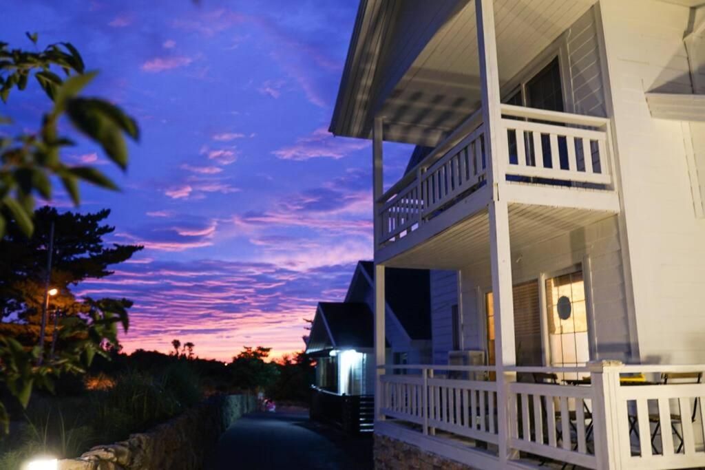 a house with a porch with a sunset in the background at Jeju Polaris Pension in Jeju