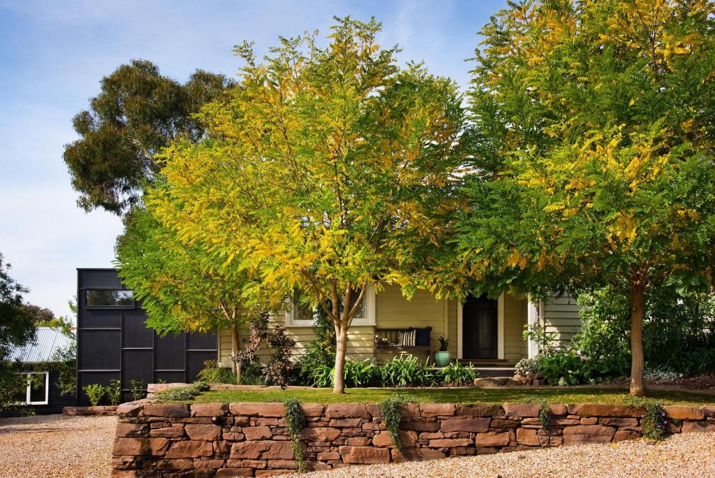 a house with trees and a stone wall at The Clubhouse in Hepburn