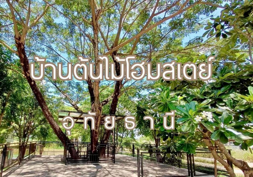 una señal frente a un árbol en un parque en บ้านต้นไม้โฮมสเตย์อุทัยธานี, en Uthai Thani
