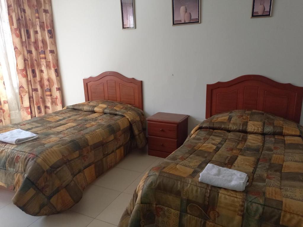 a bedroom with two beds and a dresser and curtains at HOSTAL SUMITA HOUSE_INN in Puno