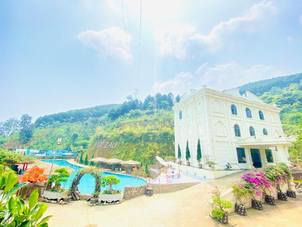 a building with a swimming pool next to a mountain at Khu du lịch sinh thái Cỏ Lau Village in Làng Song Ca