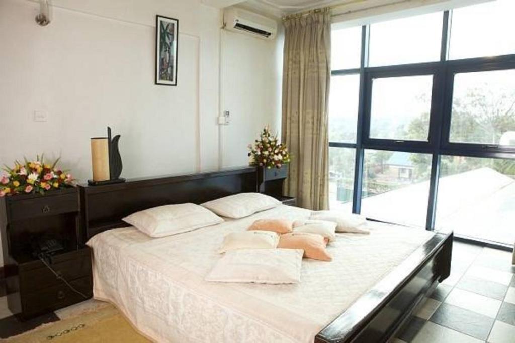 a bedroom with a large bed with white sheets and pillows at Ivys Hotel in Kampala