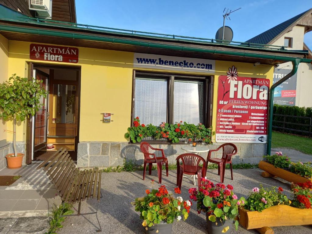 a restaurant with chairs and flowers in front of it at Apartman Flora in Benecko
