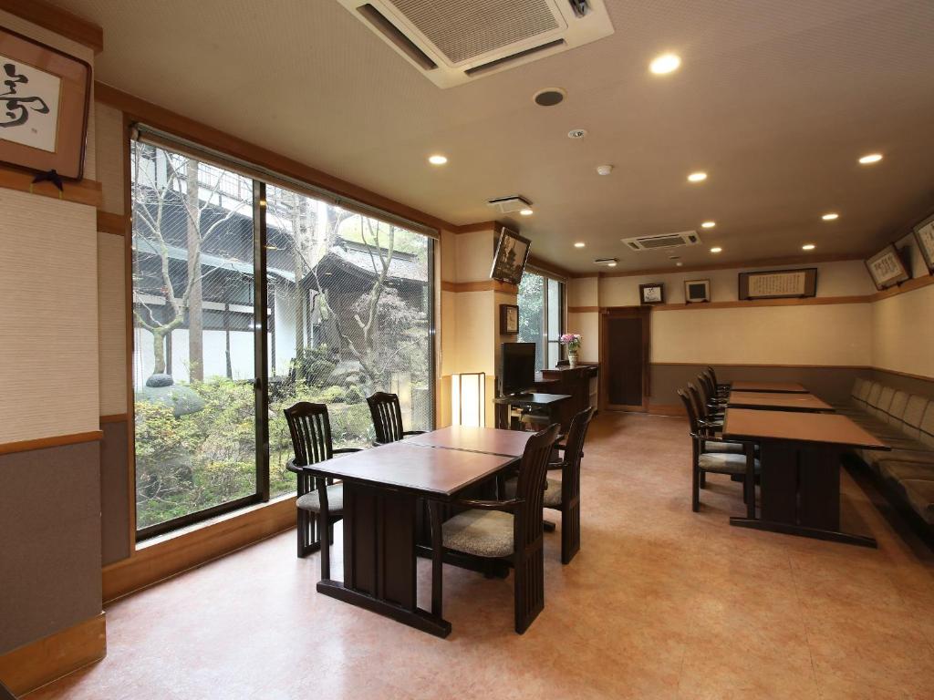 a restaurant with tables and chairs and a large window at Kisoji no Yado Iwaya in Kiso