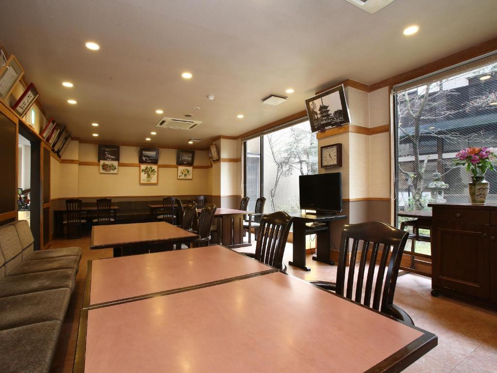 a restaurant with tables and chairs and a television at Kisoji no Yado Iwaya in Kiso