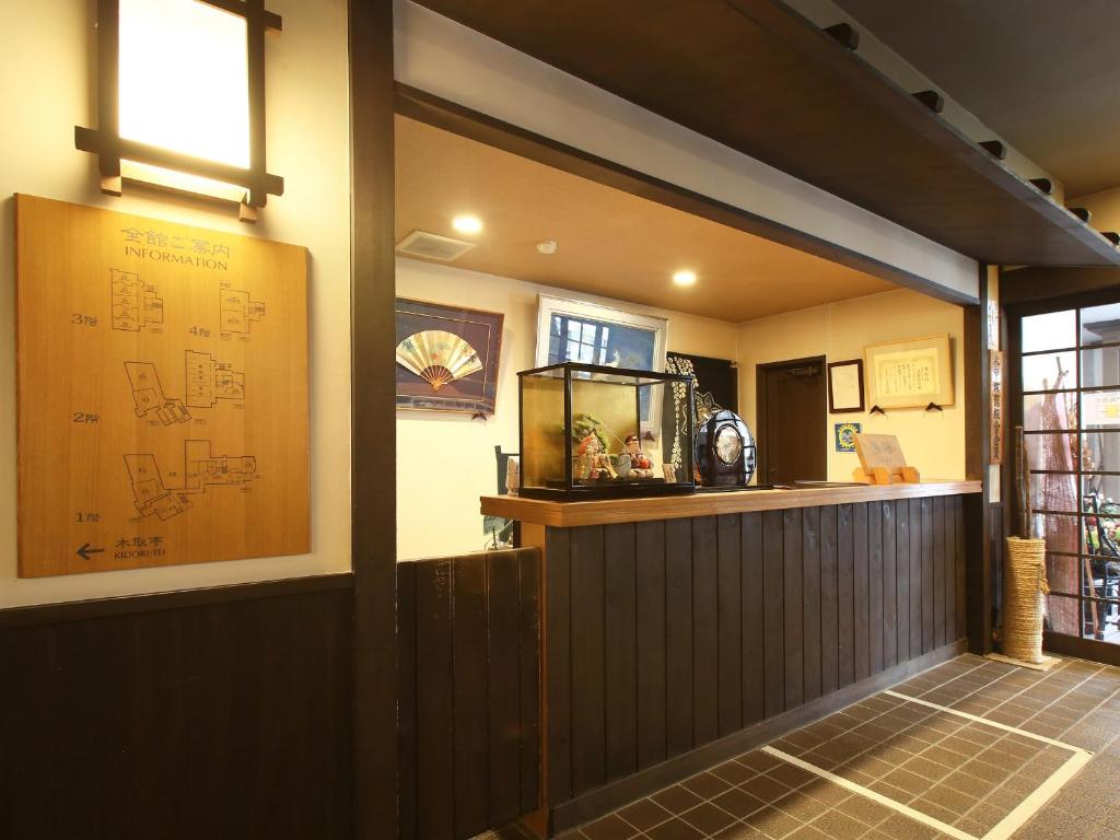 a restaurant with a bar with a fish tank on the wall at Kisoji no Yado Iwaya in Kiso