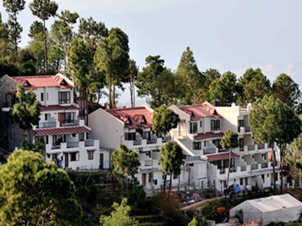a group of houses on a hill with trees at Woodsvilla Resort in Rānīkhet