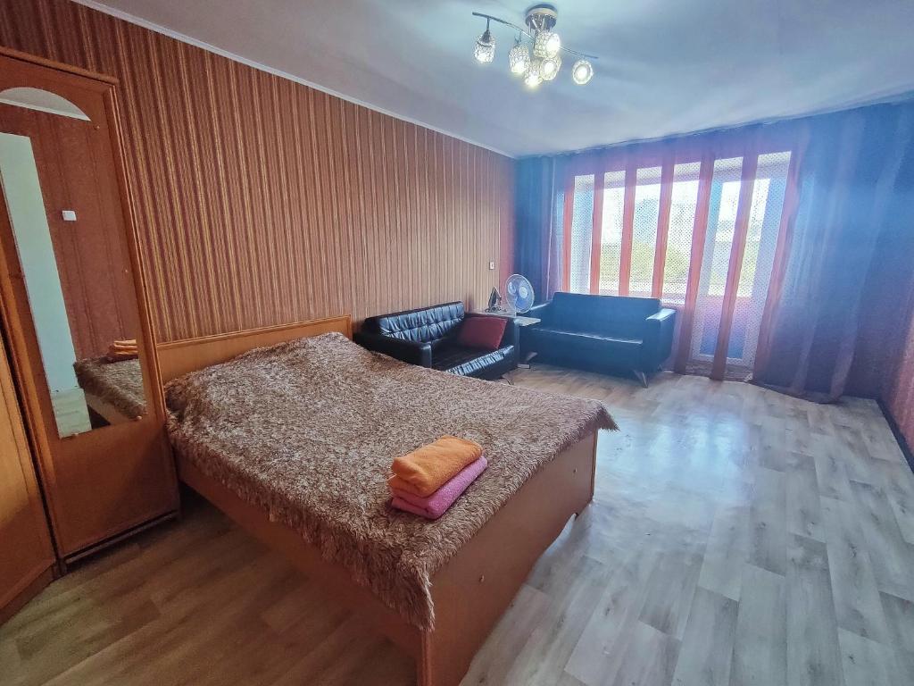 a bedroom with a bed and a couch and a chair at Galeto 22 Apartments in Semey