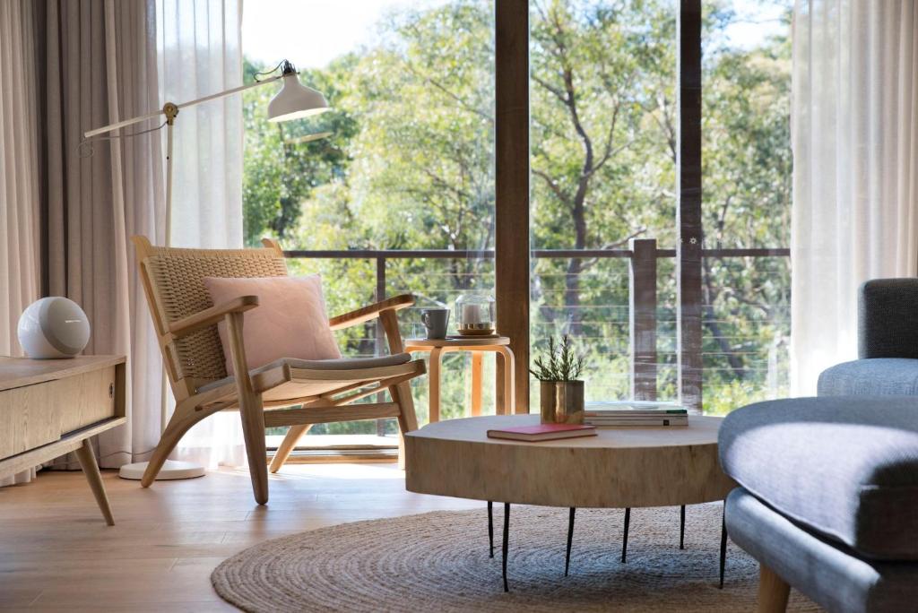 a living room with a chair and a table and a large window at Wood for the Trees in Hepburn Springs