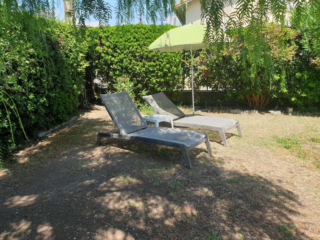 two chairs and an umbrella in a yard at Villa à 10m de la plage de sable in Vallauris
