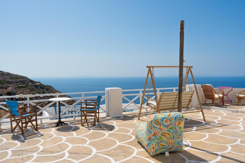 een groep stoelen en tafels op een balkon met uitzicht op de oceaan bij Sifnos in Síkinos