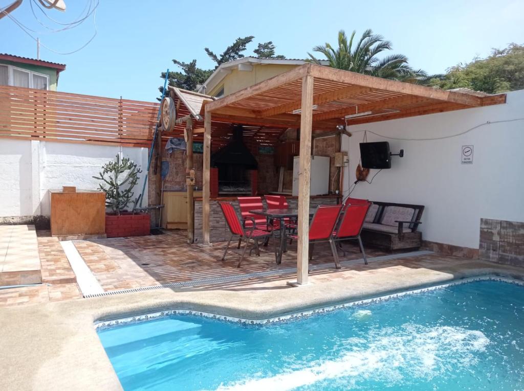 eine Terrasse mit einem Tisch, Stühlen und einem Pool in der Unterkunft Cómoda casa con piscina in Arica