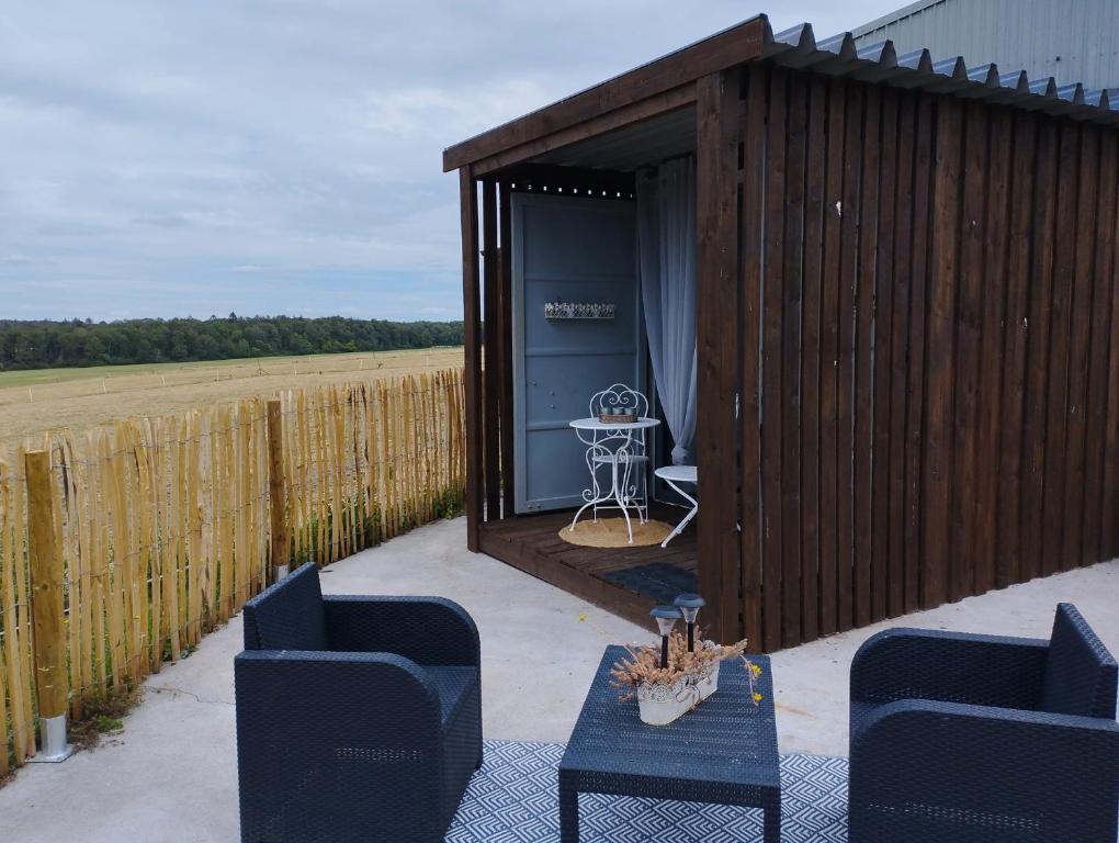 een houten schuur met een tafel en stoelen voor een veld bij La cabane du berger du parc national ESM in Froid-Chapelle